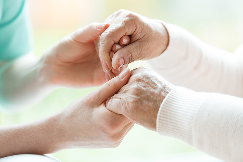 close up of a health care professional holding both hands of a senior patient