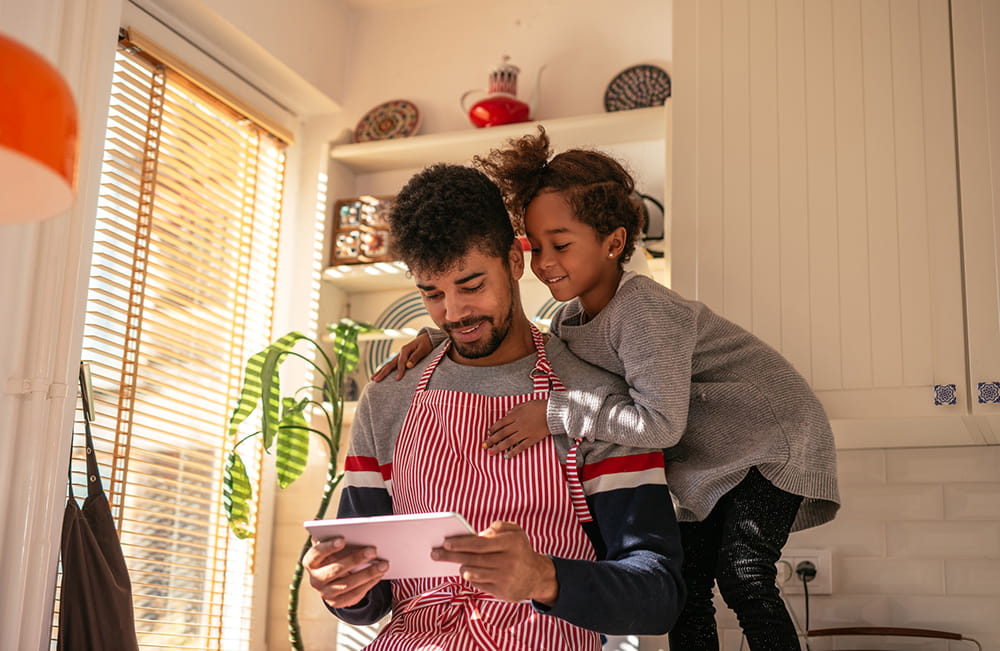 hija ayudando a su padre con una receta en la tableta