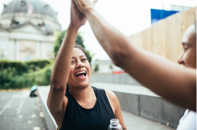 Dos mujeres chocando los cinco al aire libre