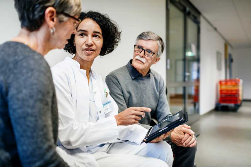 Doctor reviewing chart on tablet with patients