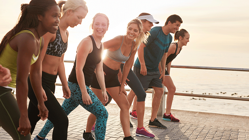 Grupo de personas sonriendo en la playa y preparándose para una carrera