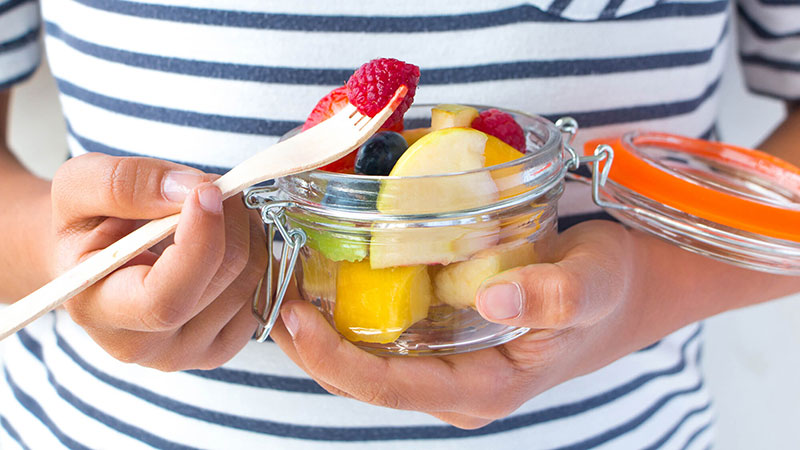 Persona con una jarra de frutas variadas