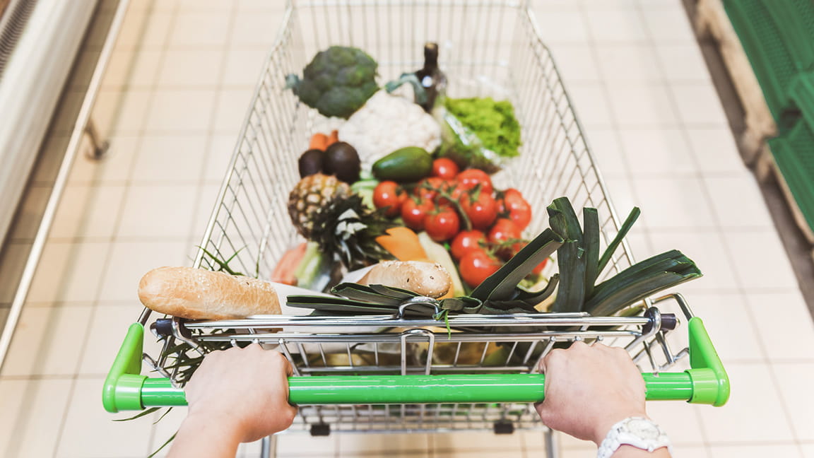 manos empujando el carrito de supermercado por un pasillo de la tienda