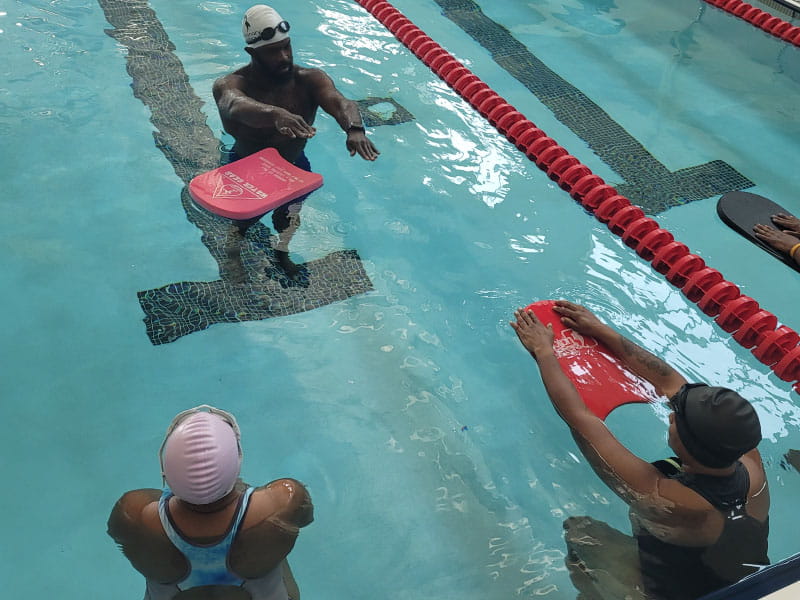 Brandon King (top), Tanika Smith (right) and Carmellia Jones (left) during a swim class at the West Charlotte High School pool in Charlotte, North Carolina. King learned to swim a few years ago and is now an instructor. (Photo courtesy of Nadine Ford)