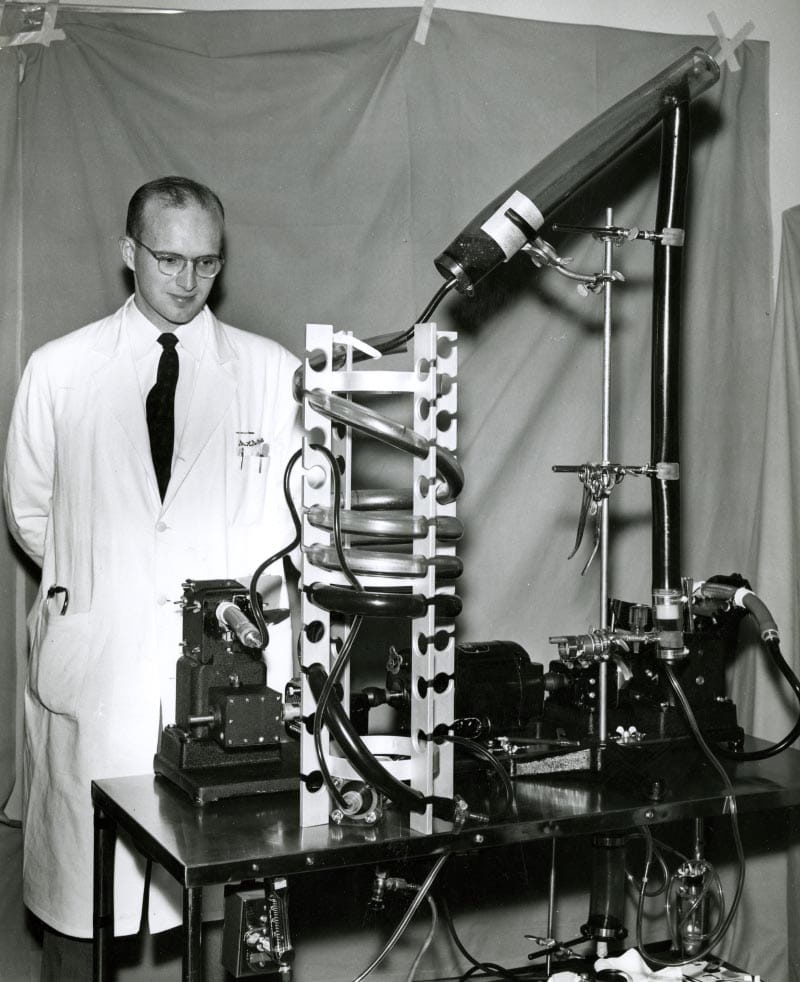 Dr. Richard DeWall in November 1956 with the heart-lung machine called a bubble oxygenator, which he developed. Used during heart surgery, the inexpensive and simple arrangement of cylinders and tubing rerouted the patient's blood, mixing it with oxygen. (Photo courtesy of University of Minnesota Archives)