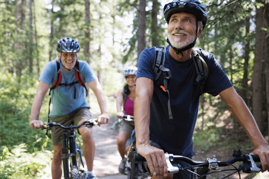 三个骑自行车穿越树林的成年人