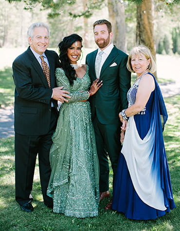 Steve, Dhivya, Danny y Deb posan para una fotografía familiar de boda al aire libre.