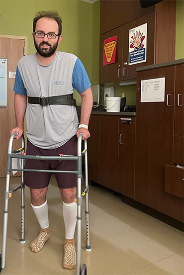 Stroke survivor, Rory Polera, is walking in a medical office with the aid of a walker.