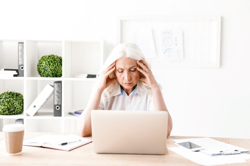 mujer confundida sentada frente a una computadora portátil