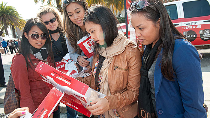 mujeres que leen la caja del kit de RCP usando solo las manos