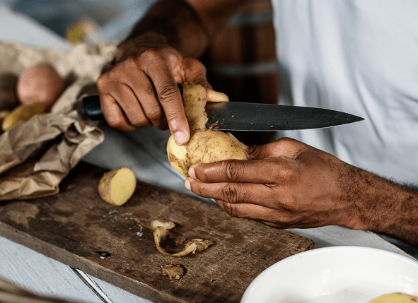 Primer plano de un hombre pelando patatas