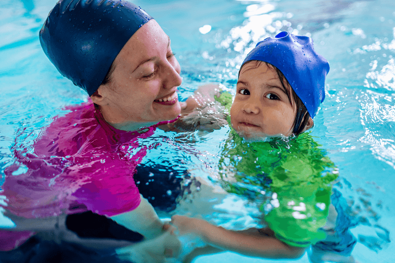 Niño en clases de natación con un adulto