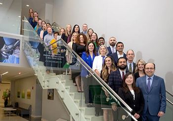 foto grupal del personal de ProMedica Stroke Network (Red de Ataque o Derrame Cerebral ProMedica) sonriendo de pie en una escalera, en un entorno de oficina