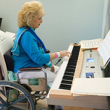 Ingrid Clarfield está sentada en su silla de ruedas tocando el piano.